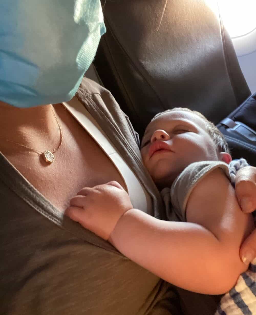 sleeping baby on plane mom wearing mask sleeping baby mom wearing mask on plane