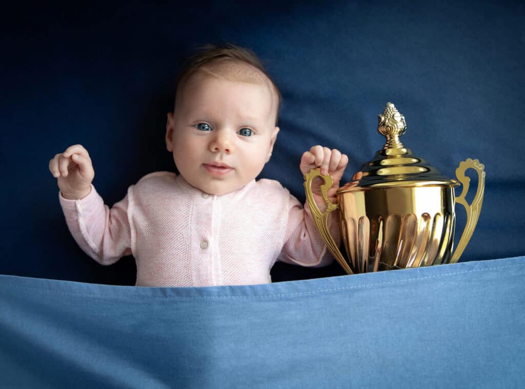 baby under covers with trophy