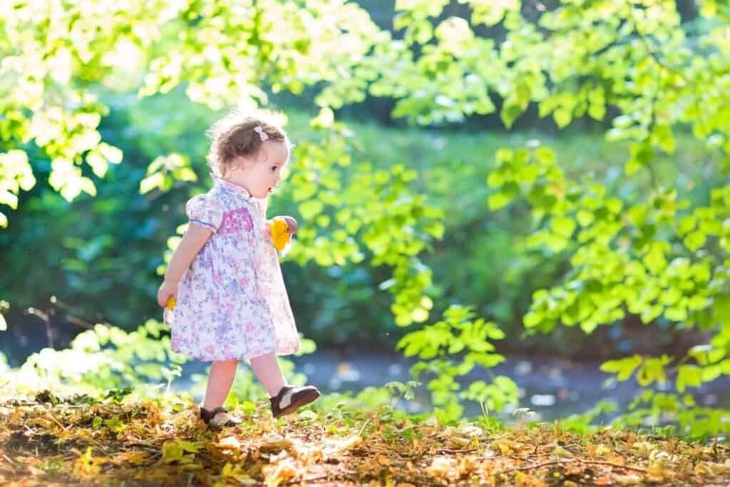 little girl walking amongst trees
