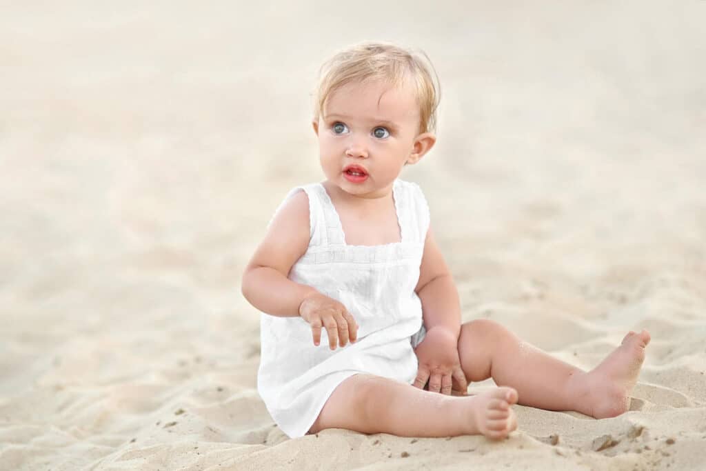 blonde baby girl sitting beach
