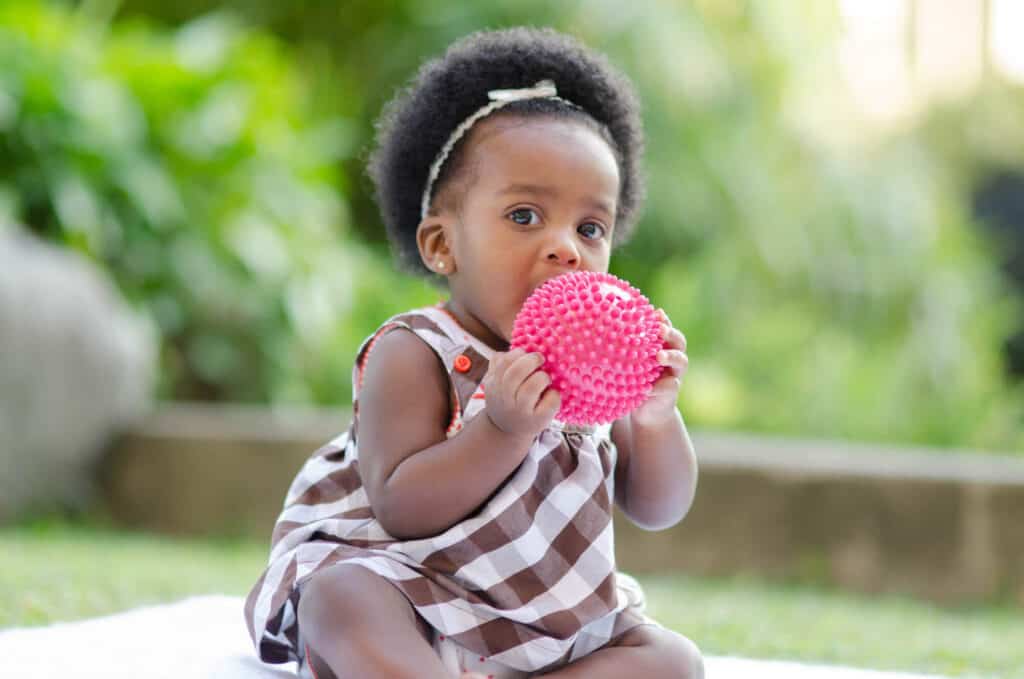 baby girl of color holding ball
