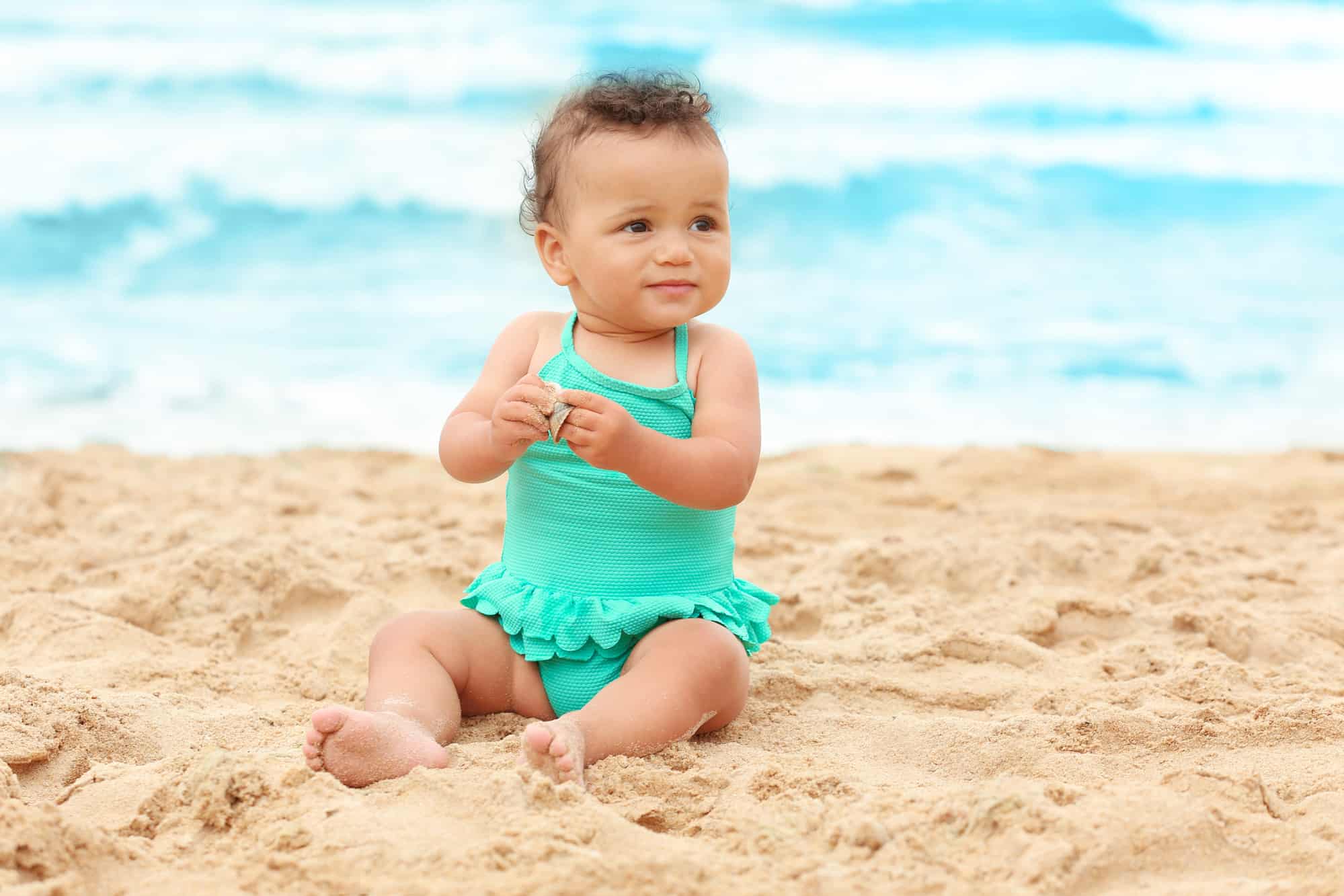 baby girl sitting beach bathing suit