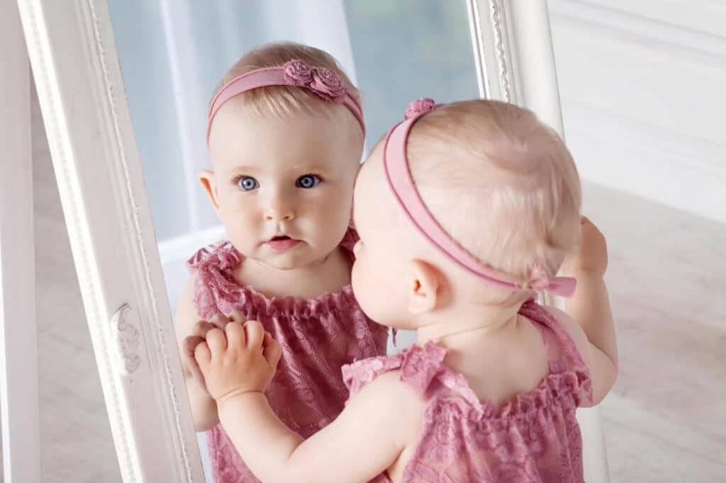 blonde baby girl looking in mirror