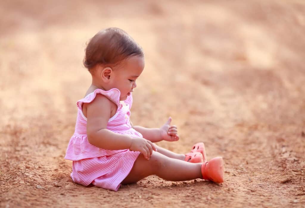 baby girl sitting in dirt earth