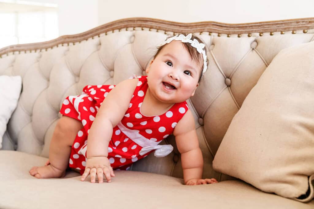 baby girl smiling on couch red dress