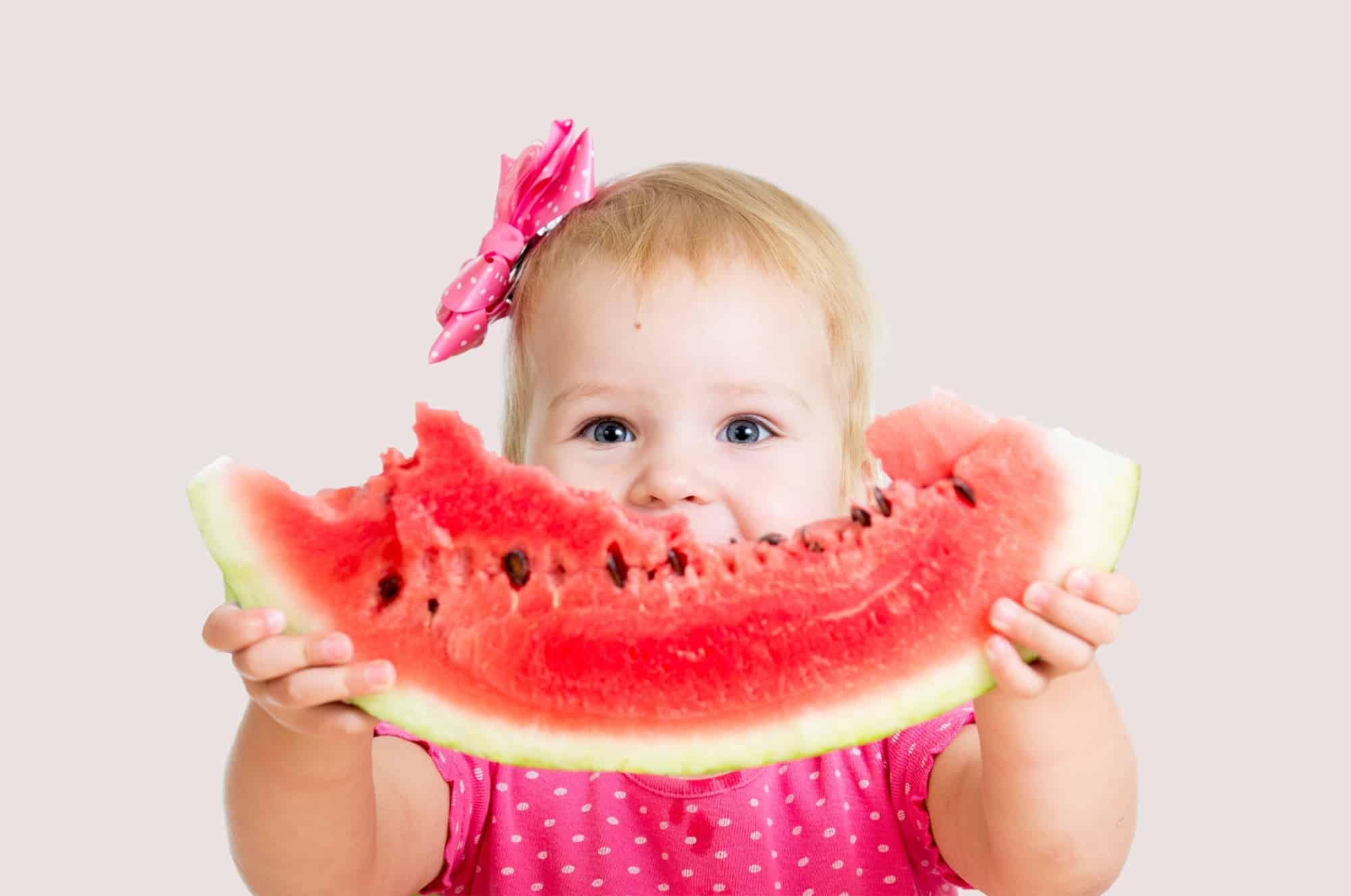 baby girl eating big piece watermelon