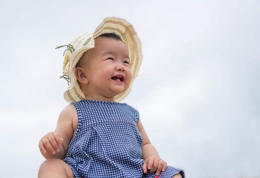baby girl with sun hat sky background