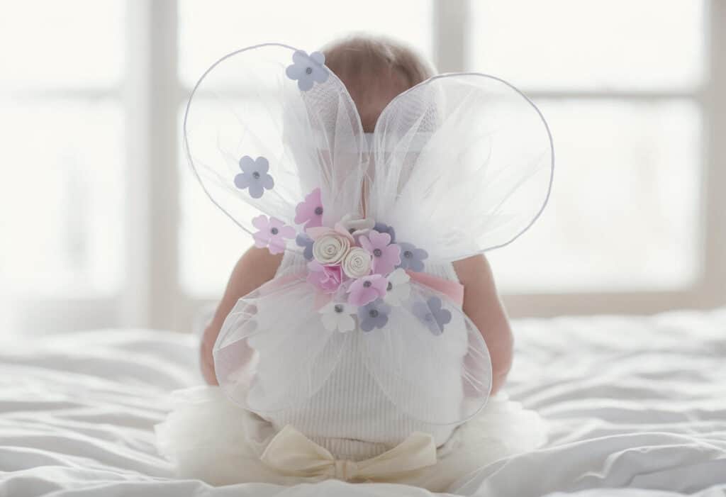 baby girl with wings sitting on bed