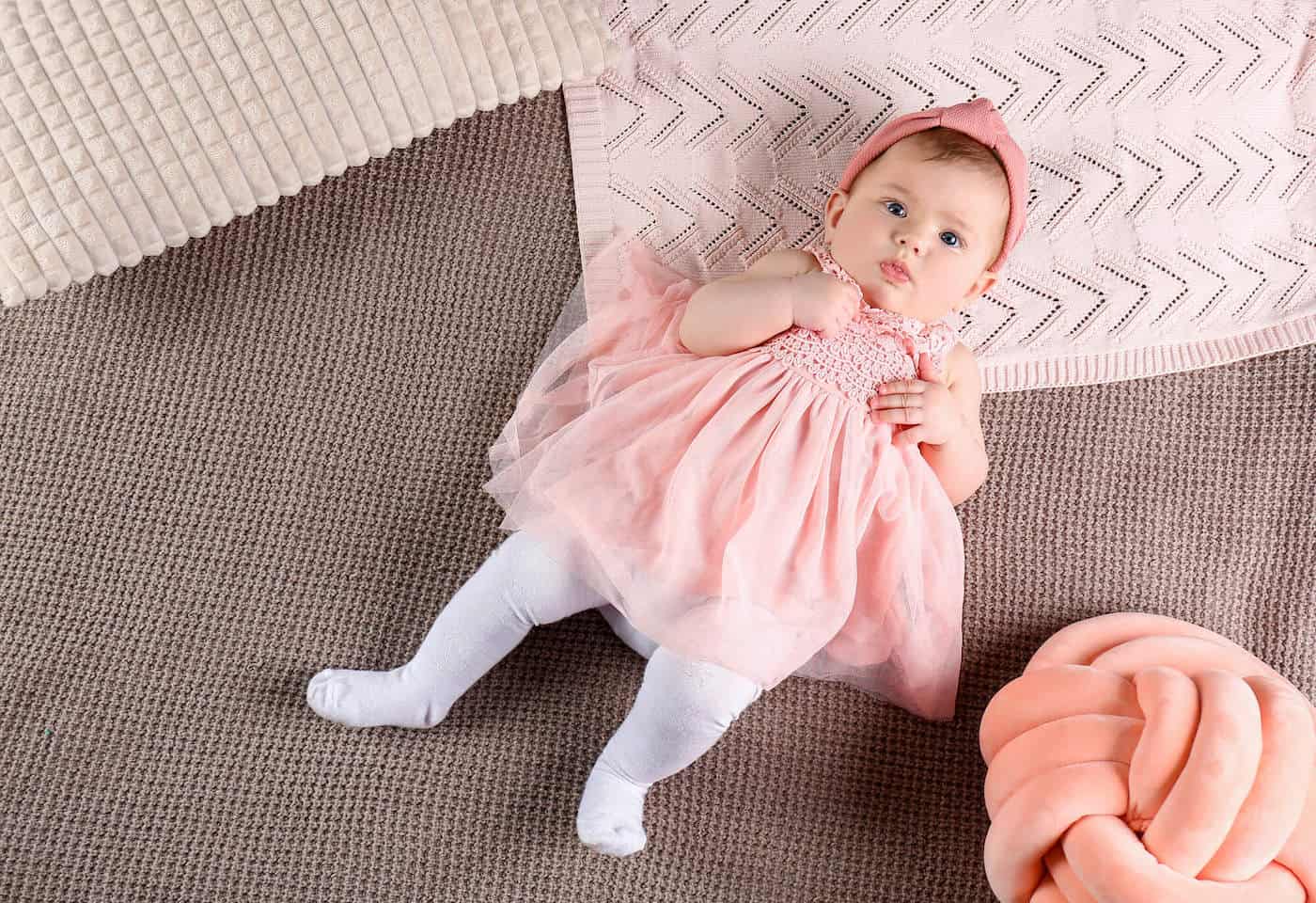 baby girl lying on back pink dress