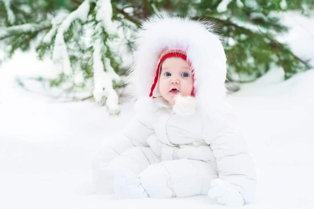 baby girl sitting in snow bundled up