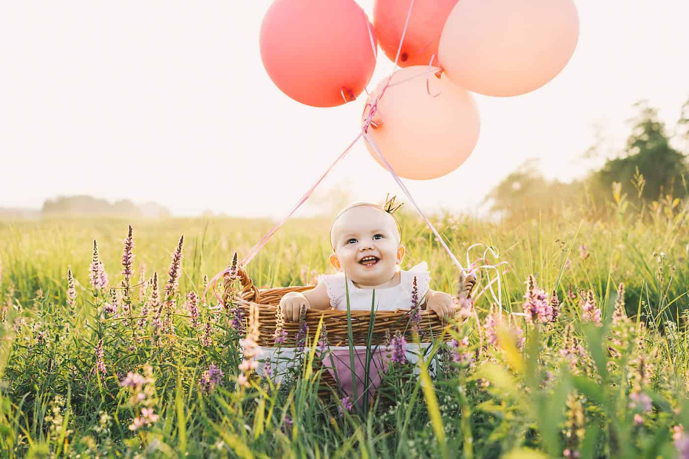 baby girl with balloons in field