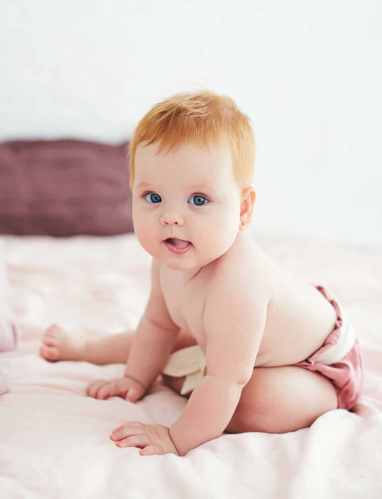 redhead baby girl sitting on bed