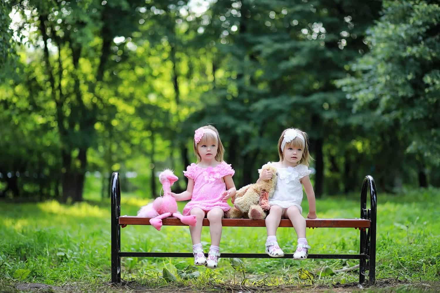 twin sisters sitting on bench in nature
