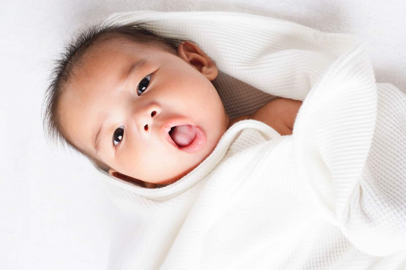 baby boy with open mouth in white towel