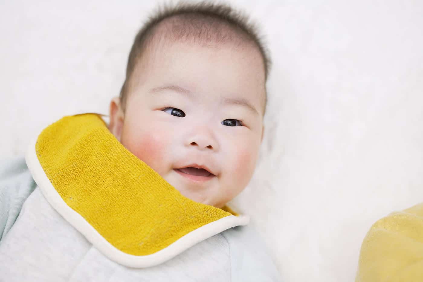 baby boy smiling yellow bib