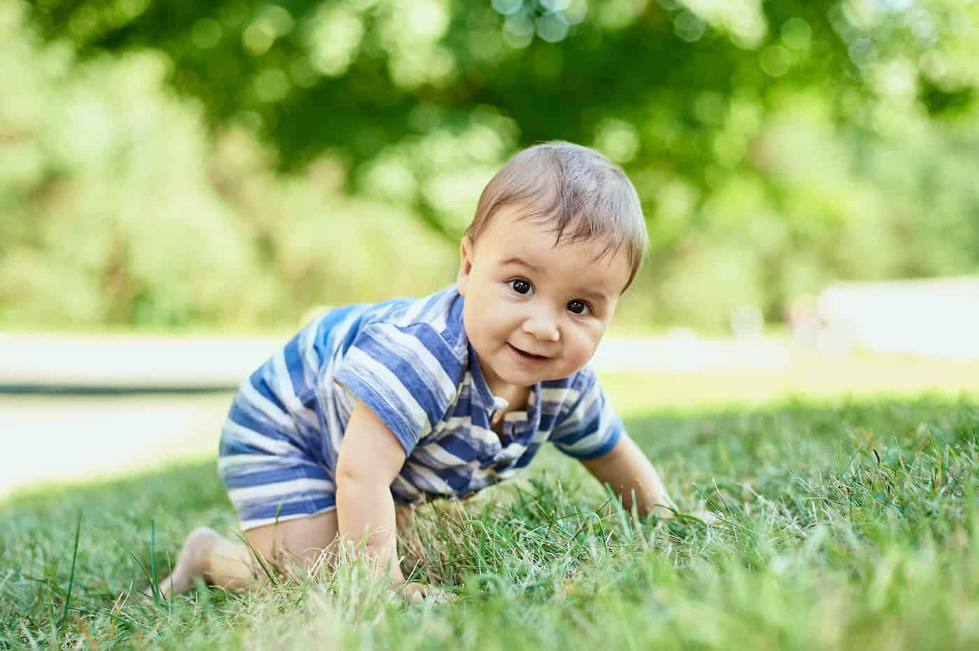 earthy baby boy crawling in grass outside