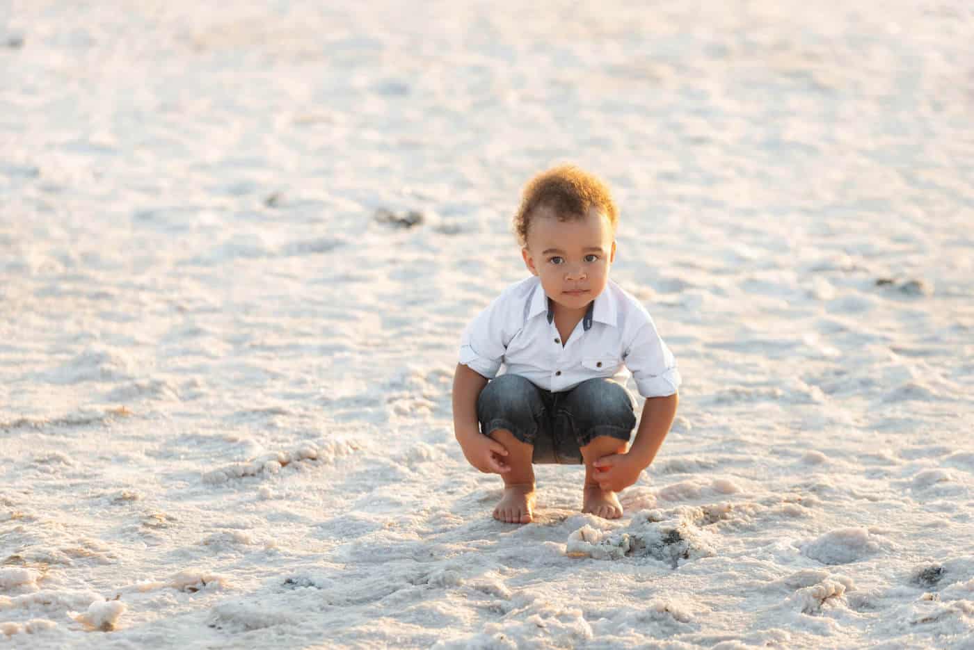 handsome baby squatting on exotic beach