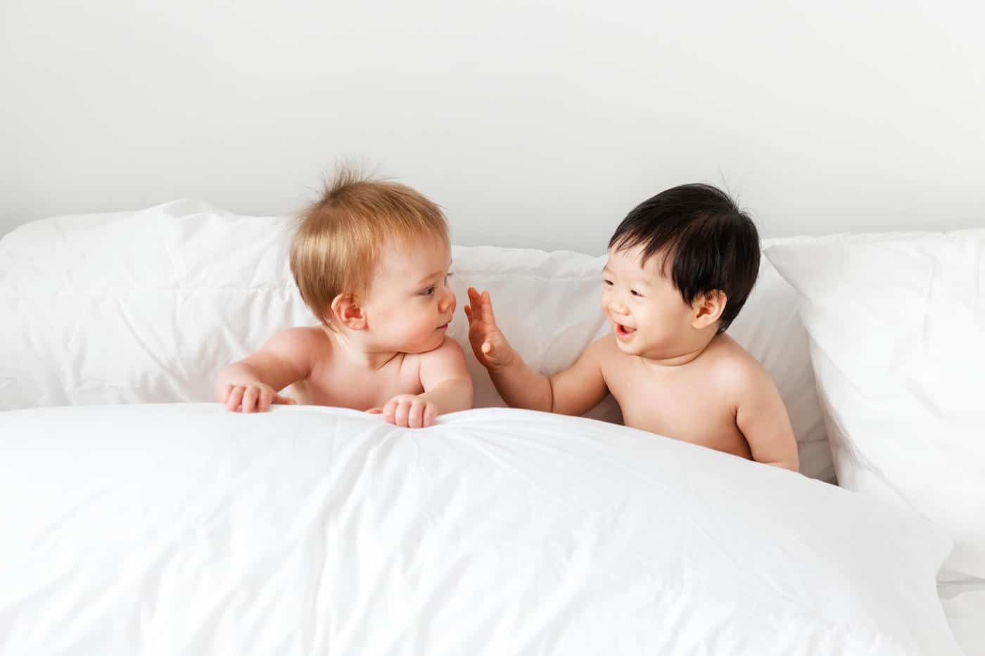 two baby boys sitting in bed