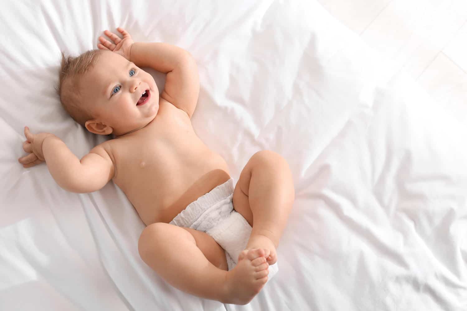 smiling baby boy lying on bed