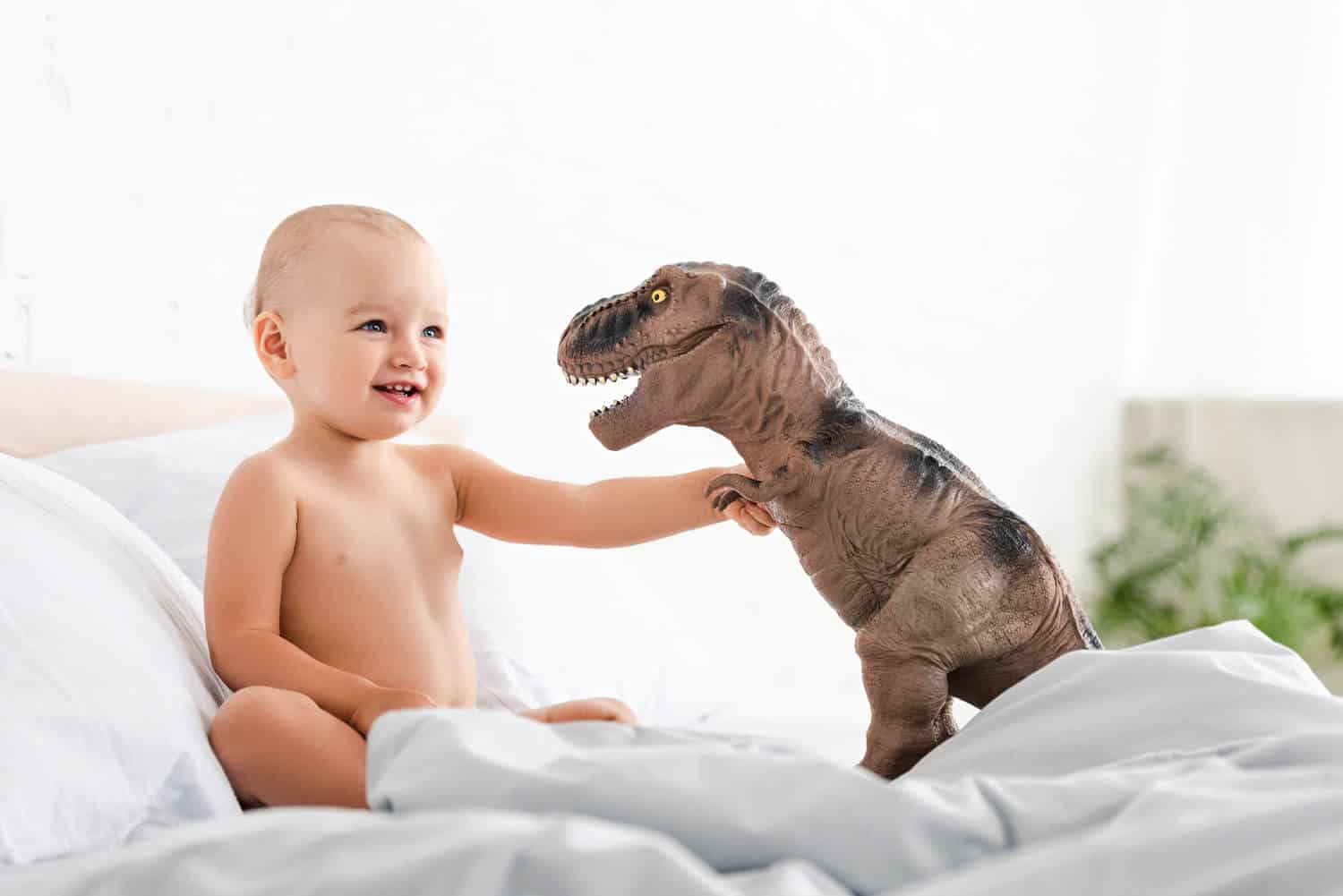 baby boy facing dinosaur